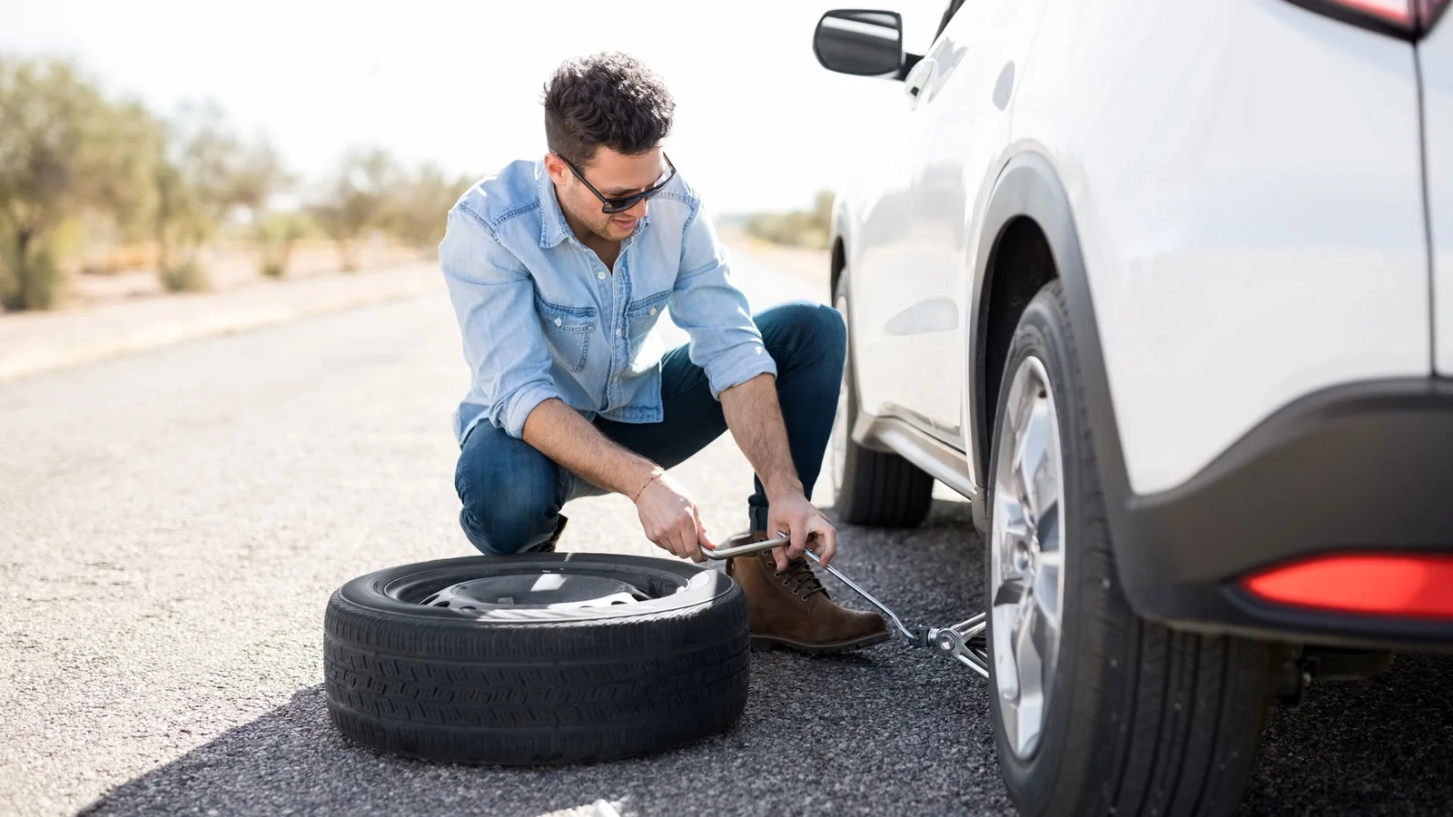 Mobile tyre fitter changing a car tyre at customer's location